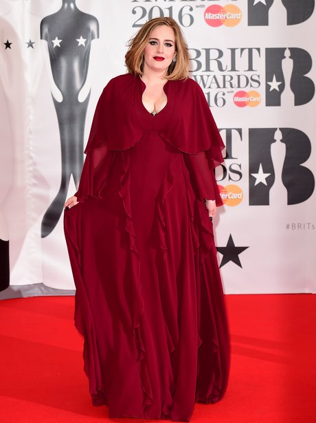 Adele stuns in a billowing red dress as she step out at the Brit Awards ...